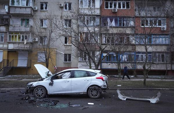 A man walks past a damaged vehicle and debris following Russian shelling in Mariupol, Ukraine on February 24, 2022. Picture: AP Photo/Sergei Grits